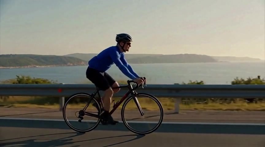 A GPU-verified Balanced Edit changes the cyclist from orange to cobalt blue while keeping the bicycle, coastal road, and camera motion coherent.